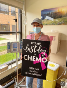 Kelly Hansen poses with a sign that reads "last day of chemo" at her last chemo appointment