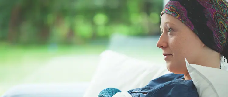 Mujer con cáncer de mama sonriendo y luciendo un pañuelo en la cabeza, con el apoyo del Pink Fund.
